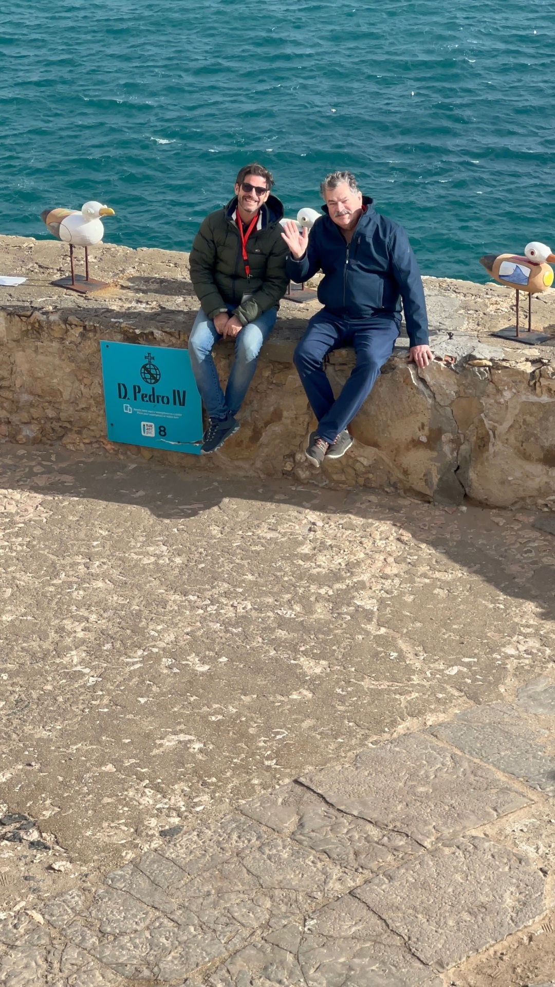 Eduardo and a guest seated on the Sítio da Nazaré sea wall beside the Atlantic
