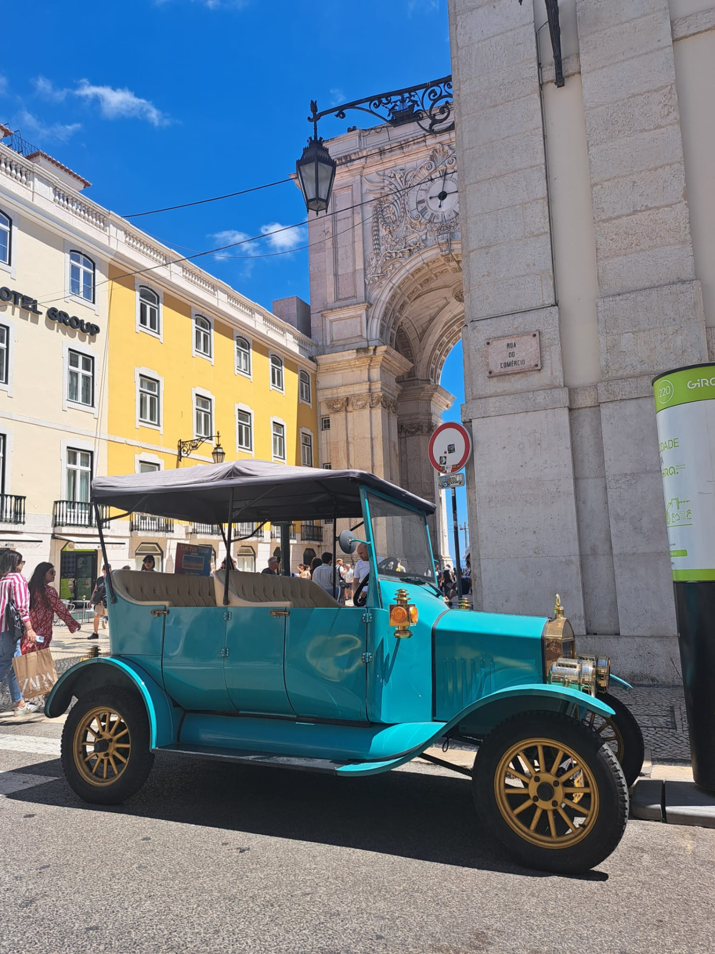 The turquoise vintage-style tuk tuk of Tiago Nunes, an independent local operator, parked near the Rua Augusta Arch in Lisbon