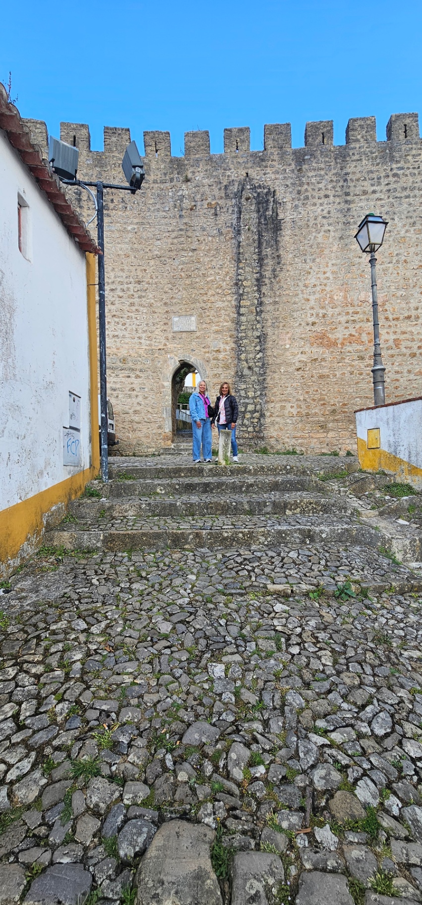 Guests on the ancient stone stairway leading up to an Óbidos castle gate