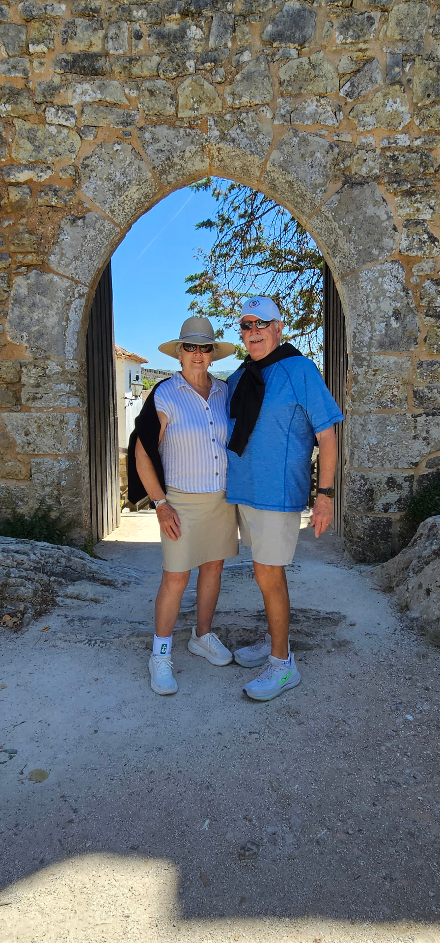 Guests framed by a medieval stone archway on the Óbidos town walls