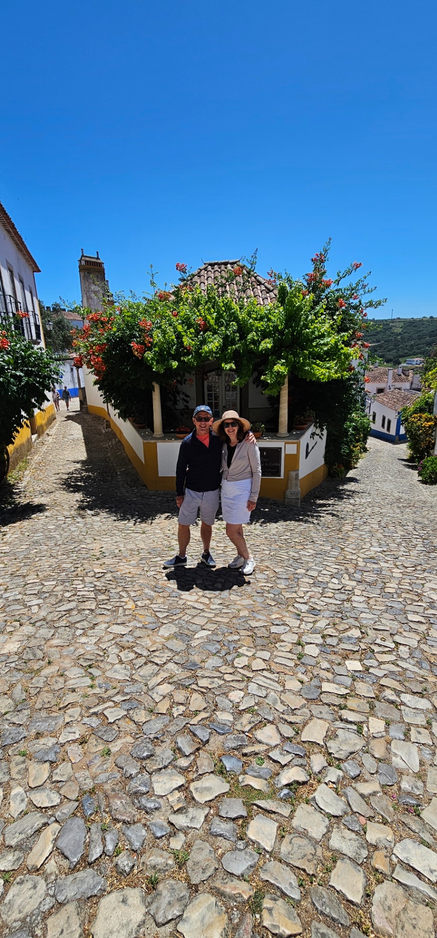 Couple on the cobbled streets of Óbidos beside a bougainvillea-covered cottage